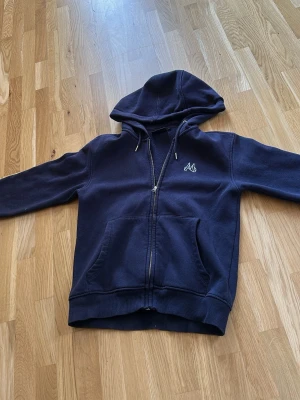 Maggiore tröja marinblå - Säljer en marinblå hoodie från Maggiore köpt för 749. i storlek S i junior passar nån som är mellan 160-165. Ett stort tryck med skidmotiv på ryggen.Perfekt för dig som gillar streetwear och sportig stil.