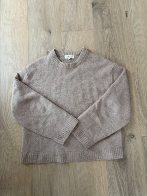 Beige stickad tröja Gina Tricot Xs - Mysig beige stickad tröja från Gina Tricot i ullblandning. Tröjan har rund halsringning, långa ärmar och ribbade muddar vid ärmslut och nederkant. Perfekt för lager på lager och enkel att matcha med jeans eller kjol. Strl Xs, ursprungs pris 399kr