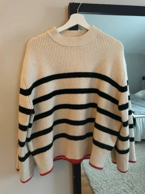 Randig stickad tröja från Zara - Beige stickad tröja från Zara med röda  detaljer vid ärmslut, strl S💕