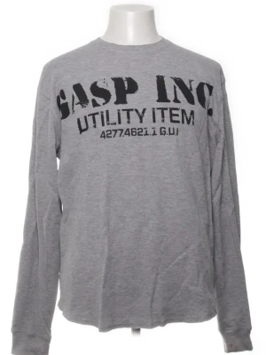 Grå långärmad topp från GASP INC - Snygg grå långärmad topp från GASP INC med tryck framtill och mindre logga på ryggen. Tillverkad i mjuk bomull och har en avslappnad passform. Perfekt för dig som gillar streetwear och vill ha en enkel men cool träningsstil