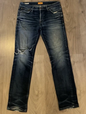 Mörkblå jeans  - Feta jeans från Jack&jonnes. Dom har ett hål vid knät. Storleken är 34/34 men sitter som en 33/33. Midjan är 44 cm och längden på hela är 108cm. 