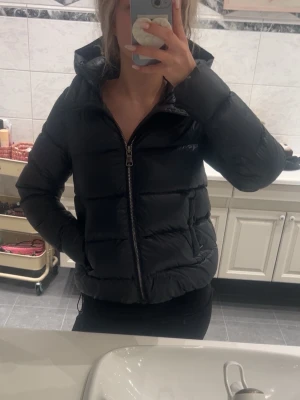 mörkblå pufferjacka från Colmar - Snygg mörkblå pufferjacka från Colmar med glansig finish och vadderad design. Jackan har huva, dragkedja framtill och Colmar-logga på ärmen. helt nytt skick. köptes för 7000, pris går att diskutera 🩷