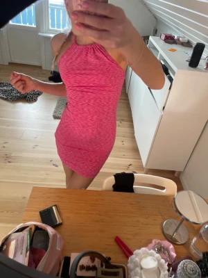 Rosa halterneck kortklänning - Säljer en rosa, tight halterneck klänning med melerad effekt. Klänningen är kort och har öppen rygg med knyt i nacken. Perfekt för dig som vill ha en enkel men snygg look. Materialet är väldigt skönt kcg stretchigt. Kan passa alla från XS/M skulle jag säga.