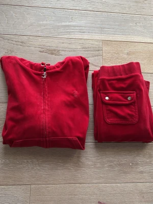 Rött juicy set! - Säljer detta jättefina juicy setet köpt för ca 3 år sedan så de har lite slitage bland annat lite fläckar och missfärgningar men annars inga defekter alls tröjan är storlek L men det är barn storlek så skulle säga att den är m-s och byxorna är storlek s!!❤️