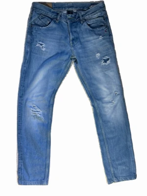 Ljusblå slitna dondup jeans med  hål - Säljer ett par ljusblå jeans med flera slitningar och hål. Som ni ser på bilderna är jeansen lagade så hålen går inte igenom. Gör att det blir gula symbolen runt om(inget man ser på avstånd). Skick 6/10