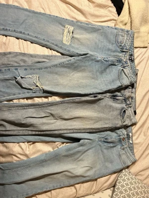 Tre par ljusblåa mom jeans - 3 par jeans säljes för 200kr  Till vänster:  Missguided, stl 34.  Använda men mycket bra skick  Mitten:  Never denim, stl XS Använda men mycket bra skick.  Till höger: NA-KD, stl 32 Använda i bra skick med en rem för skärp har släppt.