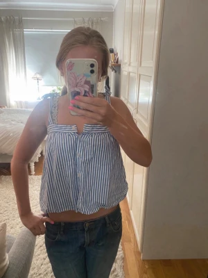 Randig topp/linne - Söt blå vit randig topp/linne med knappar framtill. Banden går att knyta om och även justera längden på, knapparna fram går att knäppa upp! Perfekt vår/sommar topp!!🌸🌸