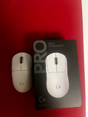 Logitech Pro X Superlight 2 mus - Trådlös gamingmus från Logitech, modell Pro X Superlight 2, i vit färg. Musen har en minimalistisk och ergonomisk design med slät yta och tydliga knappar. Botten har texten 'super' och glidytor i PTFE samt aluminiumskiktad glasyta.✅Trådlös ✅ 5 programmerbara knappar  ✅ HERO 2‑sensor ✅ Lättviktig design (~60 g) ✅ LIGHTFORCE hybridknappar ✅ Upp till ~95 timmars batteritid snabb på ladda med ✅ Rapporteringsfrekvens upp till ~8000 Hz/2000 Hz ✅ USB‑C anslutning & laddning  ✅ Inbyggt minne ✅Super Glas