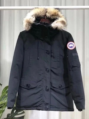 Svart parkas från Canada Goose - Snygg svart parkas från Canada Goose med stor huva kantad av äkta päls. Jackan har flera praktiska fickor, stora knappar framtill och klassisk Canada Goose-logga på ärmen. Perfekt för kalla dagar och riktigt varm. Materialet är slitstarkt och vindtätt.