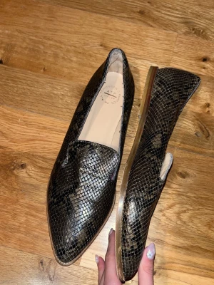 ATP atelier dervio snakeskin loafers - Säljer ett par snygga loafers från ATP atelier i modellen dervio med ormmönstrad yta i svart och brunt. Skorna har spetsig tå, låg klack och är tillverkade i ett glansigt material som ger en lyxig känsla. Nypris 3900kr. Har inte original låda tyvärr. Skriv för fler bilder eller frågor💕