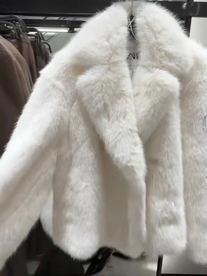 Vit pälsjacka från Zara - Snygg vit fuskpälsjacka från Zara med breda slag och rak passform. Jackan har en lyxig känsla och är perfekt för att hålla värmen under kalla dagar. Den är midjekort och har en klassisk look som passar till många olika outfits.