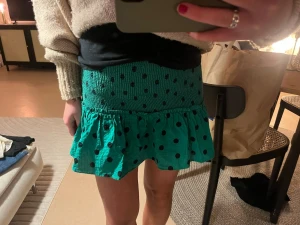 Grön prickig volangkjol - Snygg grön kortkjol med svarta prickar och volang nertill. Kjolen har smock i midjan. 🥰