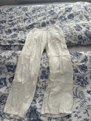 Vita linnebyxor med resårmidja - Snygga och luftiga vita linnebyxor med rak passform och resår i midjan. Perfekta för varma dagar när du vill ha en avslappnad och stilren look. Tillverkade i mjukt linne som andas.