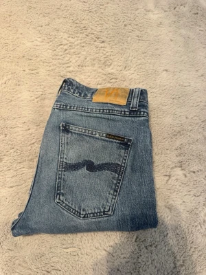 Lean Dean Nudie jeans - Säljer ett par klassiska blå jeans från Nudie Jeans med rak passform och snygg slitning. 🔥Köpta på nk för cirka 1600kr och kan tänka mig släppa dem för 399 Jensen har en slitning där fram vid gylfen men inget som syns så mycket!