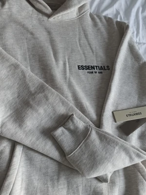 Essentials Fear of God hoodie grå - • Märke: Fear of God Essentials • Färg: Vit • Storlek: XS • Stil: Streetwear / Designer • Design: Essentials-logo på bak och bröst