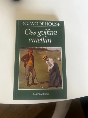 Oss golfare emellan av P.G. Wodehouse - Rolig och charmig roman av P.G. Wodehouse med grönt omslag och ett klassiskt motiv av golfspelare på framsidan. Boken är utgiven av Barbara Books och handlar om golfens värld med humoristiska berättelser från en engelsk landsortsklubb.