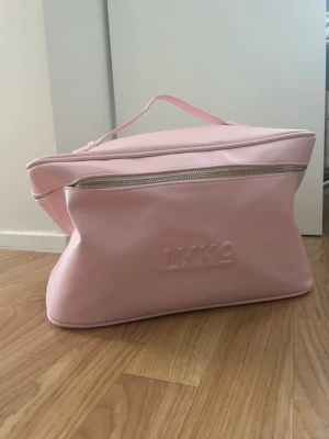 Necessär  - Säljer denna rymliga rosa necessär från Lyko. Den är i fint skick då den är helt oanvänd. Perfekt om du behöver extra förvaring för smink, hårprodukter eller resor.  Stadig, lätt att torka av och med gott om plats (se bilder).