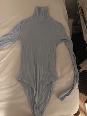 Ljusblå ribbad polobody - Säljer en ljusblå body med lång ärm och polokrage. Bodyn är ribbad och har knäppning i grenen. Skriv om ni är intresserade 🤗