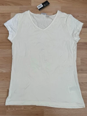 Ny. Vit v-ringad t-shirt från Esmara - Klassisk vit t-shirt från Esmara med v-ringning och korta ärmar. Tillverkad i mjuk bomull som känns skön mot huden. Enkel och stilren design som passar till allt. Perfekt basplagg för garderoben.