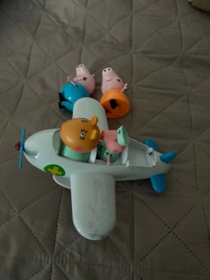 Peppa Pig flygplansleksak - Peppa Pig-leksak med vitt och blått flygplan i plast och fyra färgglada figurer från serien. Flygplanet har grönt kors på sidan och plats för figurerna att sitta i. Perfekt för dig som gillar Peppa Pig och vill ha kul med fantasilek.
