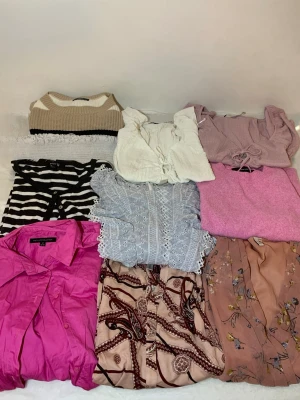 Mix av toppar i olika färger och stilar - Säljer ett paket med trendiga toppar i olika färger och material. Innehåller stickad beige/vit topp, vit omlottopp med knyt, ljuslila topp med snörning, svartvit randig topp, ljusblå spetsblus, rosa stickad topp och en chockrosa skjorta. Perfekt för dig som vill uppdatera garderoben!