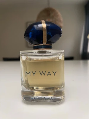 My Way parfym från Giorgio Armani - Elegant parfymflaska från Giorgio Armani, My Way. Flaskan är genomskinlig med ljusgul vätska och har ett exklusivt blått, ovalt lock med gulddetaljer. Modern och stilren design som känns lyxig och tidlös.