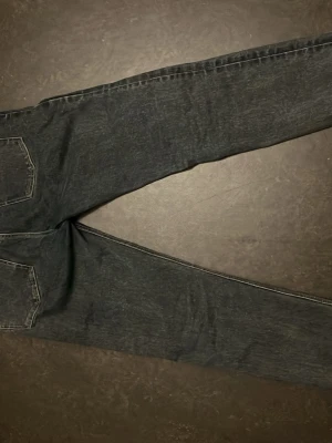Mörkblå jeans från F&A - Säljer ett par mörkblå jeans från F&A med klassisk femficksdesign och kontrastsömmar. Jeansen har rak passform och är tillverkade i slitstarkt denimtyg. Perfekta för dig som gillar en enkel och tidlös look.