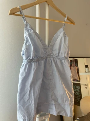 Ljusblå linnetopp med smala axelband - Snygg ljusblå linnetopp med smala axelband och v-ringad hals.  