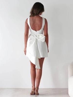 Vit kort klänning med stor rosett - Supersnygg vit kort klänning med djup urringning i ryggen och en stor dekorativ rosett bak. (Rosetten går att ta av och sätta på) Klänningen har pärldetaljer längs kanterna och en asymmetrisk volangdetalj. Perfekt för student eller annna fin tillställning! Helt oanvänd med prislappen kvar. Kunde inte ha det för det va var för liten på mig. Fantastiskt fin💖orginalpris 1200kr. Priset kan diskuteras😍