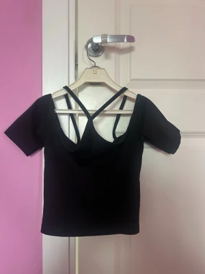 Svart y2k topp - Säljer en cool svart croptop från Asos. Snörerna ger en halterneck look. Ser lite komplicerad ut😅Om man vill ha en bild med toppen på är det bara att fråga💗