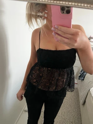 Svart spetslinnetopp med volang - Svart linnetopp med spets över hela, och öppen i ryggen! säljer även bikbok vera kostymbyxorna på bilden💕
