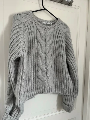 Ljusgrå kabelstickad tröja från nakd - Jättefin ljusgrå grov kabelstickad tröja från NAKD🤍🤍 Storlek S/M. Skriv gärna om de finns några frågor eller funderingar!