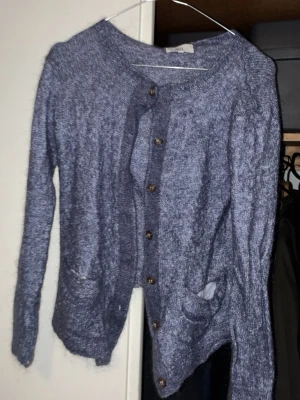 Ljuslila stickad cardigan  - Mysig ljuslila stickad cardigan med rund halsringning och träknappar framtill. Koftan har två framfickor och långa ärmar. Perfekt för lager på lager och en chill look. Skulle säga att de är mer M än L