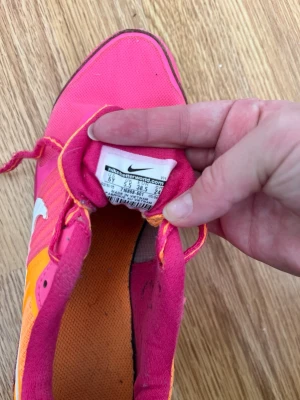 Nike rosa och orange sneakers - Färgstarka sneakers från Nike i rosa och orange med vita detaljer och snörning.