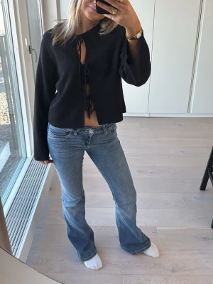 Svart croppad blus med snörning - En svart stickad tröja med knyt band framtill från Gina tricot 💕använd en gång 