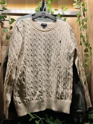  Polo Ralph Lauren - Kabelstickad vit tröja från Polo Ralph Lauren med rund halsringning och broderad logga på bröstet. Tröjan har långa ärmar och breda ribbade muddar vid ärmslut och nederkant. Perfekt för lager på lager och klassisk stil. Pris går att diskuteras vid intresse 🤩✅. Den är i storlek Xl i barn så blir som S i herr.