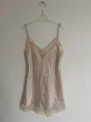 Nattlinne med spetsdetaljer - Fint nattlinne/pyjamaslinne i ljusbeige med tunna axelband och spets längs urringning och nederkant. Står ingen storlek inuti men skulle säga att det passar xs/s. Säljer då jag har många andra 💕
