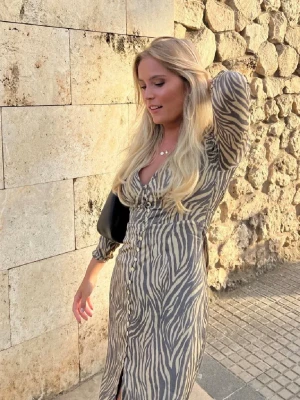 Zebramönstrad långklänning från Adoore - Säljer en långklänning från Adoore med zebramönster i beige och mörkbrunt. Helt oanvänd så i super fint skick! I modellen Adoore Paris dress🤍 Storlek 34! Är också öppen för att byta mot annan adoore klänning!