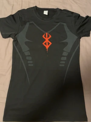 Berserk compression shirt - En tränings tshirt inspirerad av berserk den är helt ny och ny köpt. Mått: axelbrädd 41cm total längd uppifrån och ner 63cm skickas inom 1 dag