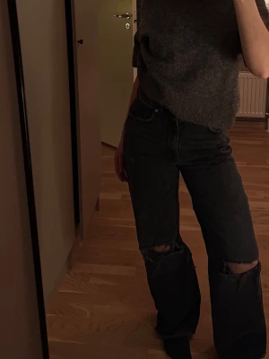Svarta vida jeans med hål - Fina nästintill oanvända jeans med hål på båda knän. Vida med lös passform. 