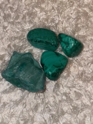 Gröna malakitstenar till smycken - Säljer fyra vackra malakitstenar i olika former och storlekar, perfekta för att använda i smyckestillverkning eller som dekoration. Stenarna har en djup grön färg med naturliga mönster och ådringar som gör varje bit unik. Passar dig som gillar kristaller och unika accessoarer.