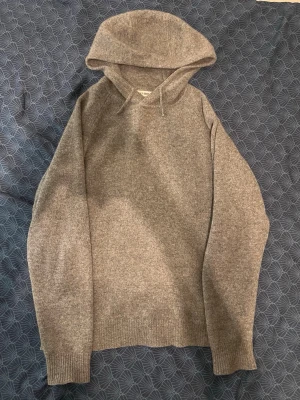 Grå hoodie från Soft Goat i cashmere - Säljer en grå hoodie från Soft Goat i mjuk och lyxig cashmere. Hoodien har klassisk huva med dragsko och ribbade muddar vid ärmslut och nederkant. Perfekt för dig som vill ha något riktigt bekvämt och stilrent. Tjockt material skiljer sig åt andra cashmere hoddies från softgoat nya vinter kollektionen. Storlek small men modellen är oversized så den sitter luftigt/medium 