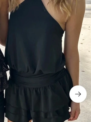 Svart volangklänning med halterneck - Snygg svart klänning med halterneck och knyt i nacken. Modellen har ett markerat midjeband. Nypris 650kr mitt pris 350. Helt ny med prislapp 