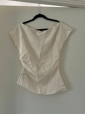 Asymmetrisk topp - Supersnygg asymmetrisk topp från Mango i cremevit. Figurnära passform Använd fåtal gånger  Inga anmärkningar