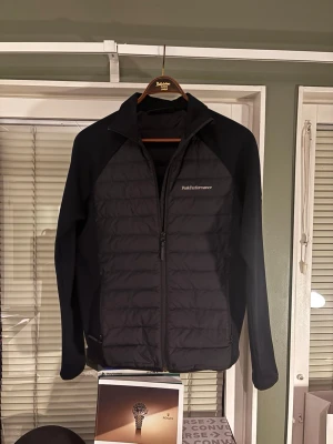 cardigan Peak Performance svart  - Snygg svart cardigan från Peak Performance. Perfekt för lager-på-lager och outdoor-aktiviteter. Tveka inte på att höra av dig vid frågor och funderingar 