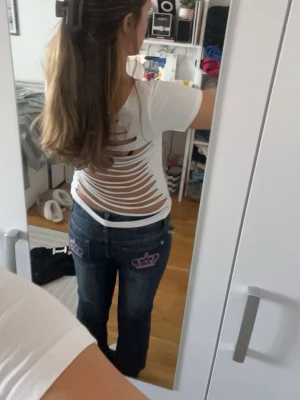 Vit t-shirt med öppen rygg och snitt - Baksidan har coola snittade detaljer som ger en öppen rygg-effekt. Perfekt för dig som vill sticka ut med en unik topp. Materialet känns mjukt och stretchigt