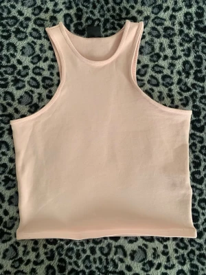 Ljusrosa linnetopp från Gina Tricot - Säljer en ljusrosa linnetopp från Gina Tricot. Toppen är ärmlös med en tight passform och har en enkel, stilren design utan mönster eller detaljer. Perfekt att matcha med jeans eller kjol för en clean look.