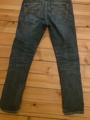 Blå jeans från Nudie Jeans - Tjena säljer ett par klassiska blå jeans från Nudie Jeans med snygg slitning. Bakfickorna har Nudie Jeans karaktäristiska broderade vågmönster. Perfekta för en avslappnad och trendig look. Passar för dig som är runt 160-170. Nypris: 1600. Mitt pris: 499. Hör gärna av er vid funderingar 🙌