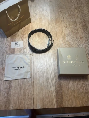 Burberry bälte  - Burberry Herr Bälte tillverkat i svart läder, storlek 85 cm. Bältet är designat för män och har en klassisk stil med märkets signaturdetaljer. Produkten levereras med originalförpackning och tillbehör.