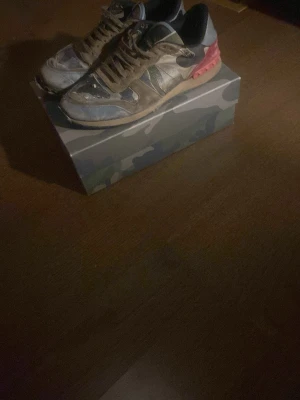 Valentino rockrunners - Snygga sneakers från Valentino i svart, grått och vitt med en cool röd detalj på hälen. Skorna har lågt skaft och klassisk snörning. Materialmix av textil och syntet för en sportig look.